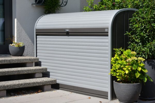 Moderne silberne Mülltonnenverkleidung neben Eingangstreppe mit Pflanzen